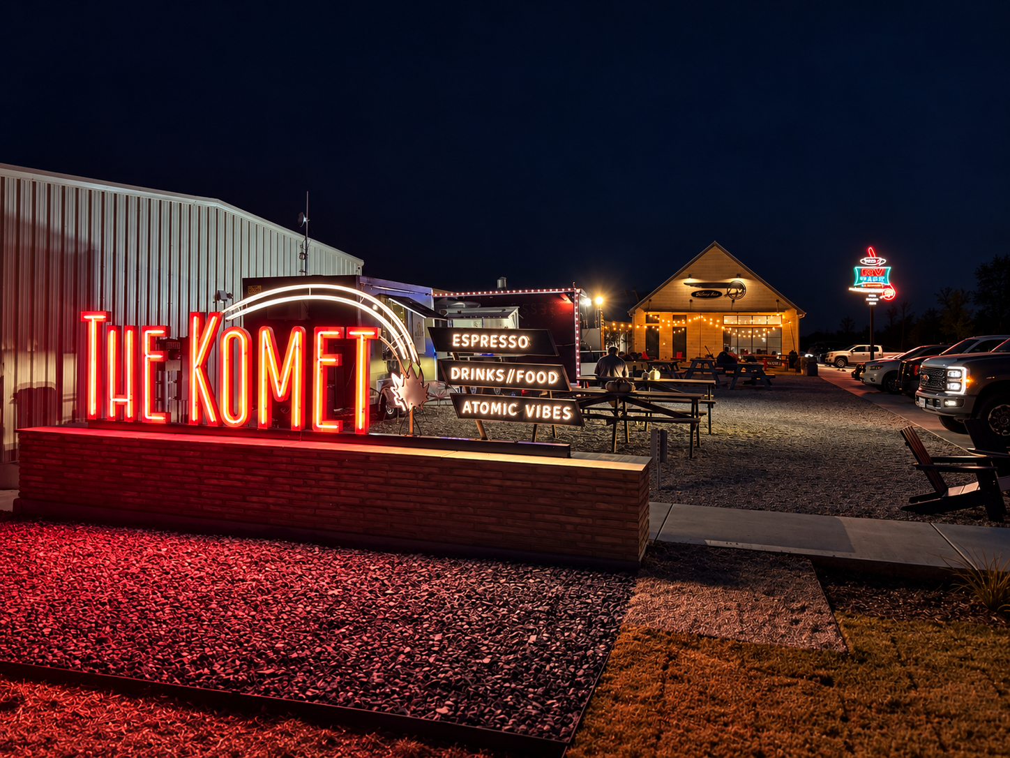 The Komet neon sign glowing red at night above the picnic tables and food trucks
